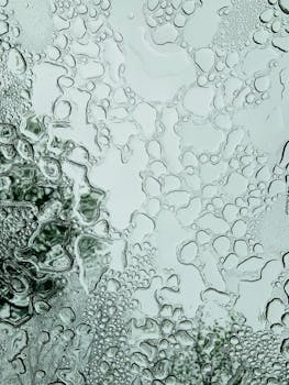 Close-up of water drops on glass creating an abstract texture with reflection.