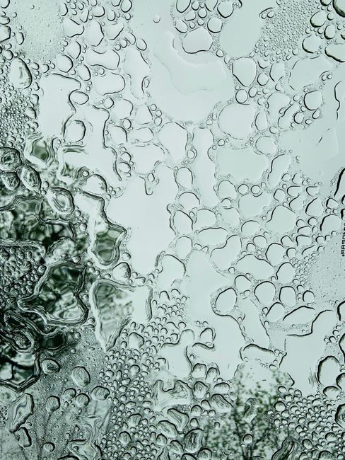 Close-up of water drops on glass creating an abstract texture with reflection.