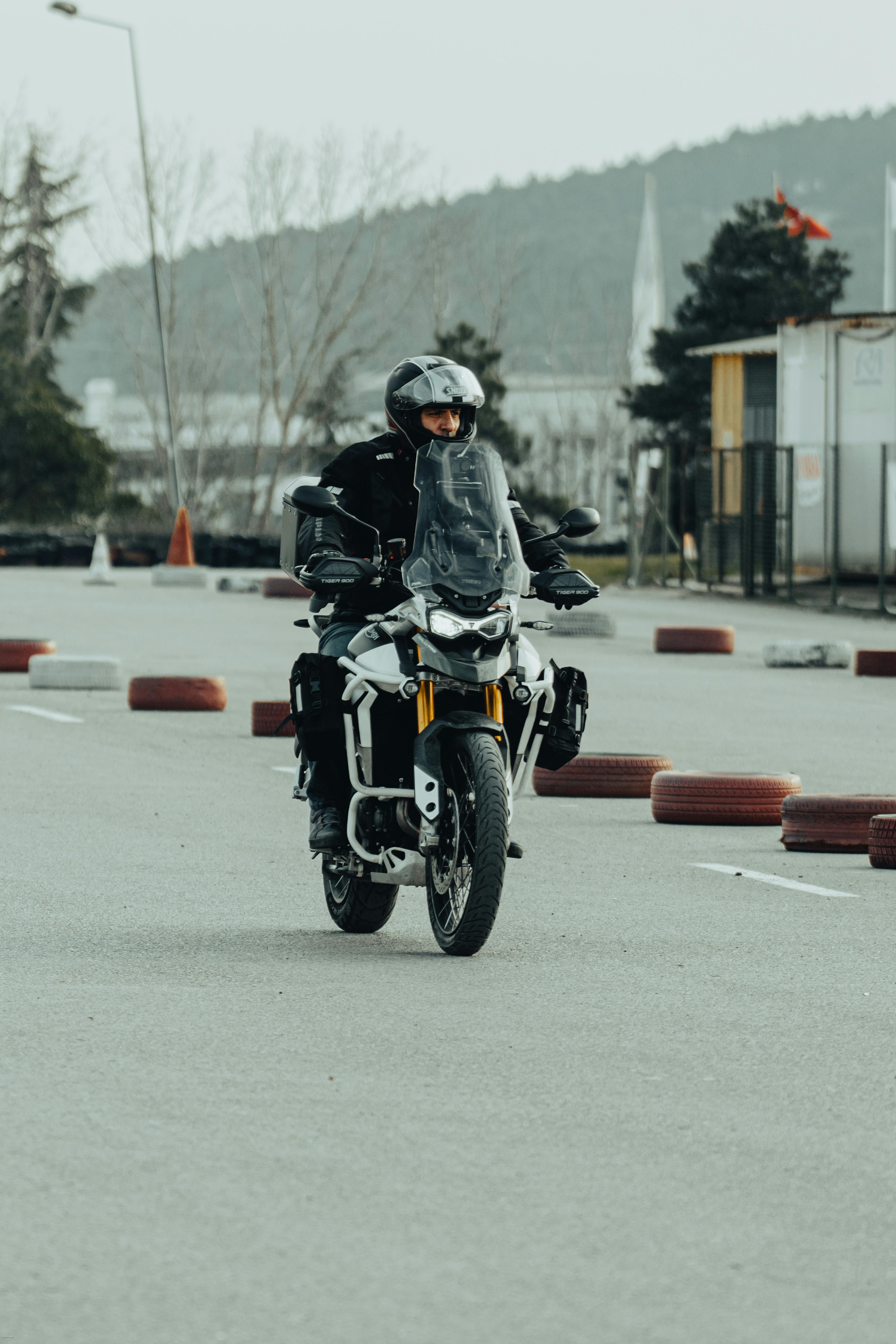 Motorcyclist riding through an outdoor training course with safety gear and helmet.