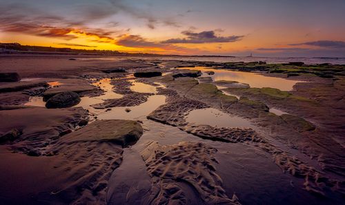 Free Enchanting coastal sunset with vibrant sky over rocky beach. Ideal for nature and travel imagery. Stock Photo