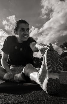Woman stretching outdoors in black and white, motivational workout scene.