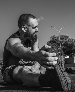 Man stretching outdoors in black and white, showcasing workout motivation.
