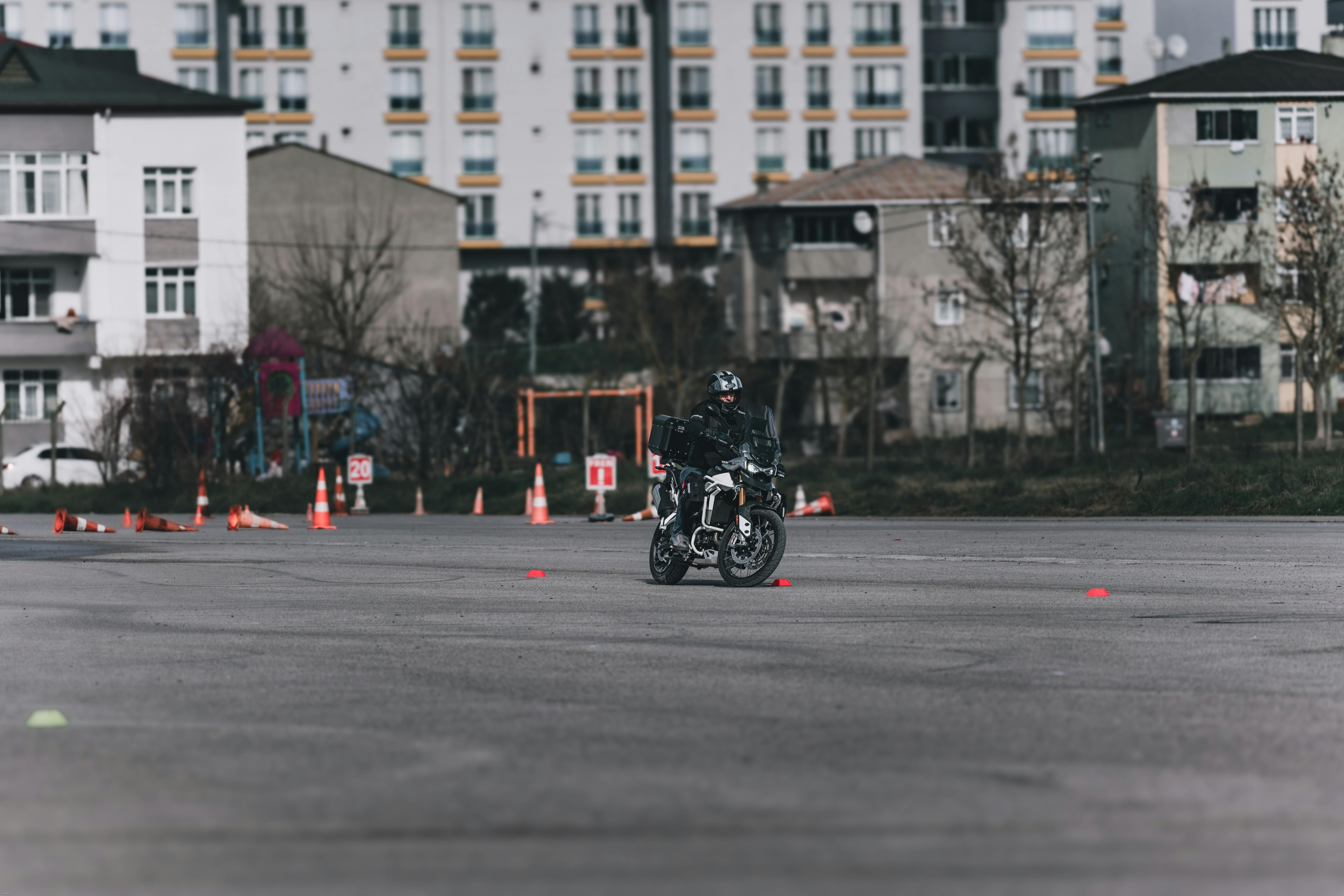 A motorcyclist navigating a traffic cone course in an urban setting, enhancing skills.