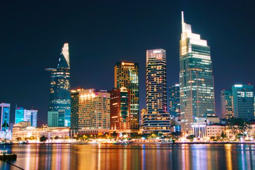Vibrant night view of Ho Chi Minh City's illuminated skyline across the river.