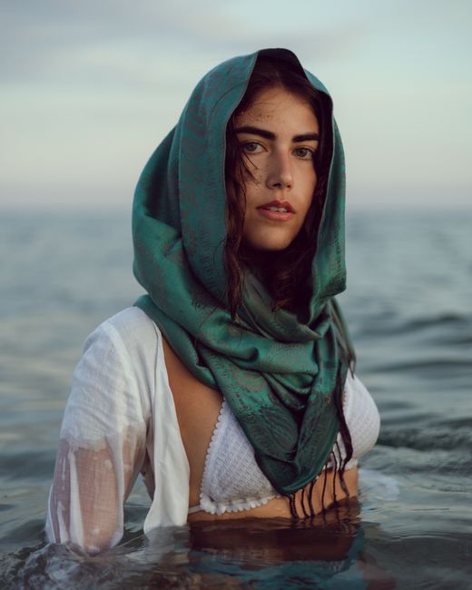 Portrait of a woman with a green scarf in ocean waters, exuding elegance and serenity.