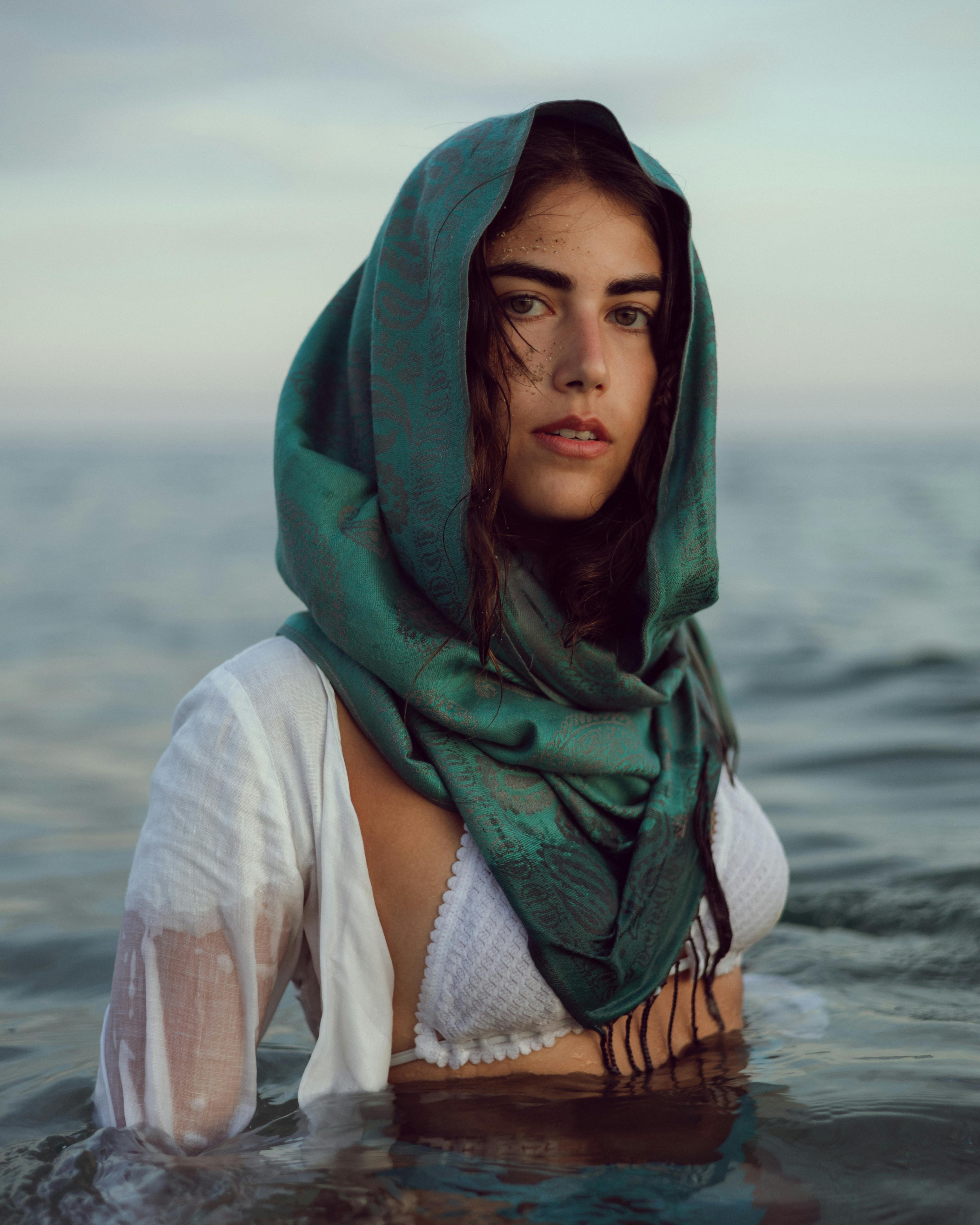gratis Portret van een vrouw met een groene sjaal in het water van de oceaan, die elegantie en sereniteit uitstraalt. Stockfoto