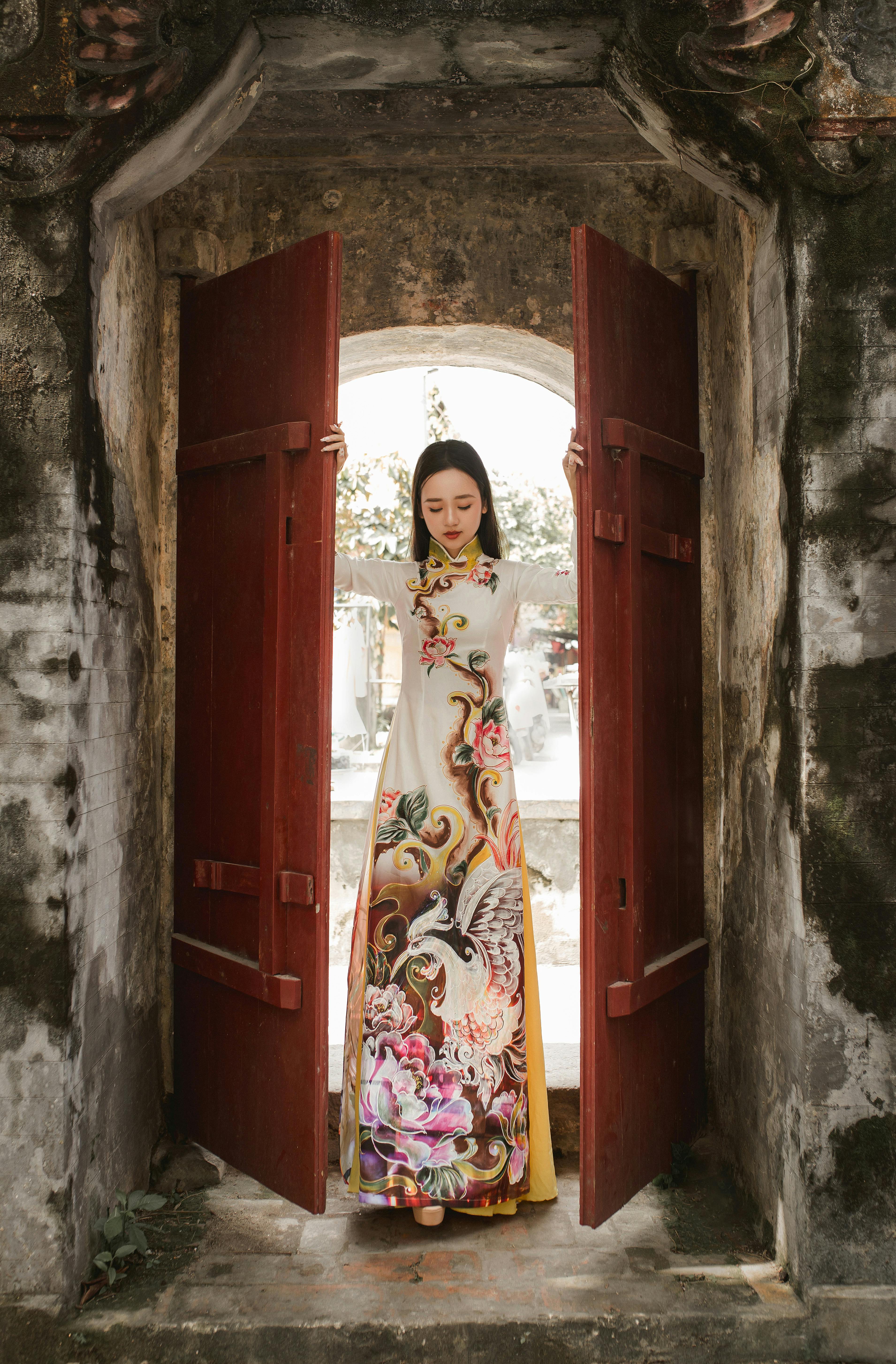 Woman in ornate Ao Dai at an ancient doorway in Hội An.