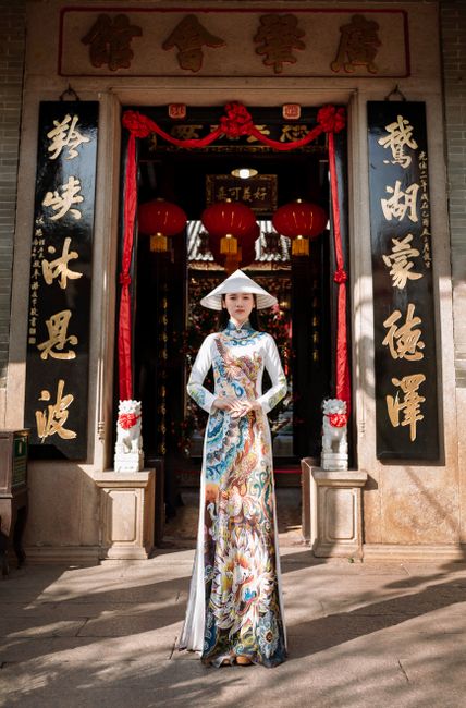 Vietnamese woman wearing ao dai standing at ancient temple in Hội An, Vietnam.