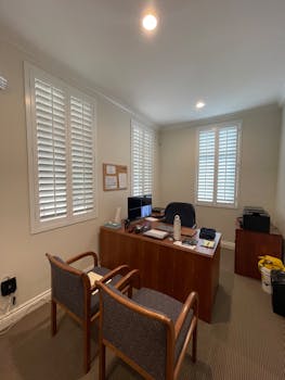A well-lit modern office with desk, chairs, and shutters creating a professional atmosphere.