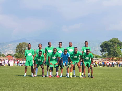 A soccer team in green uniforms poses together outdoors on a sunny day.