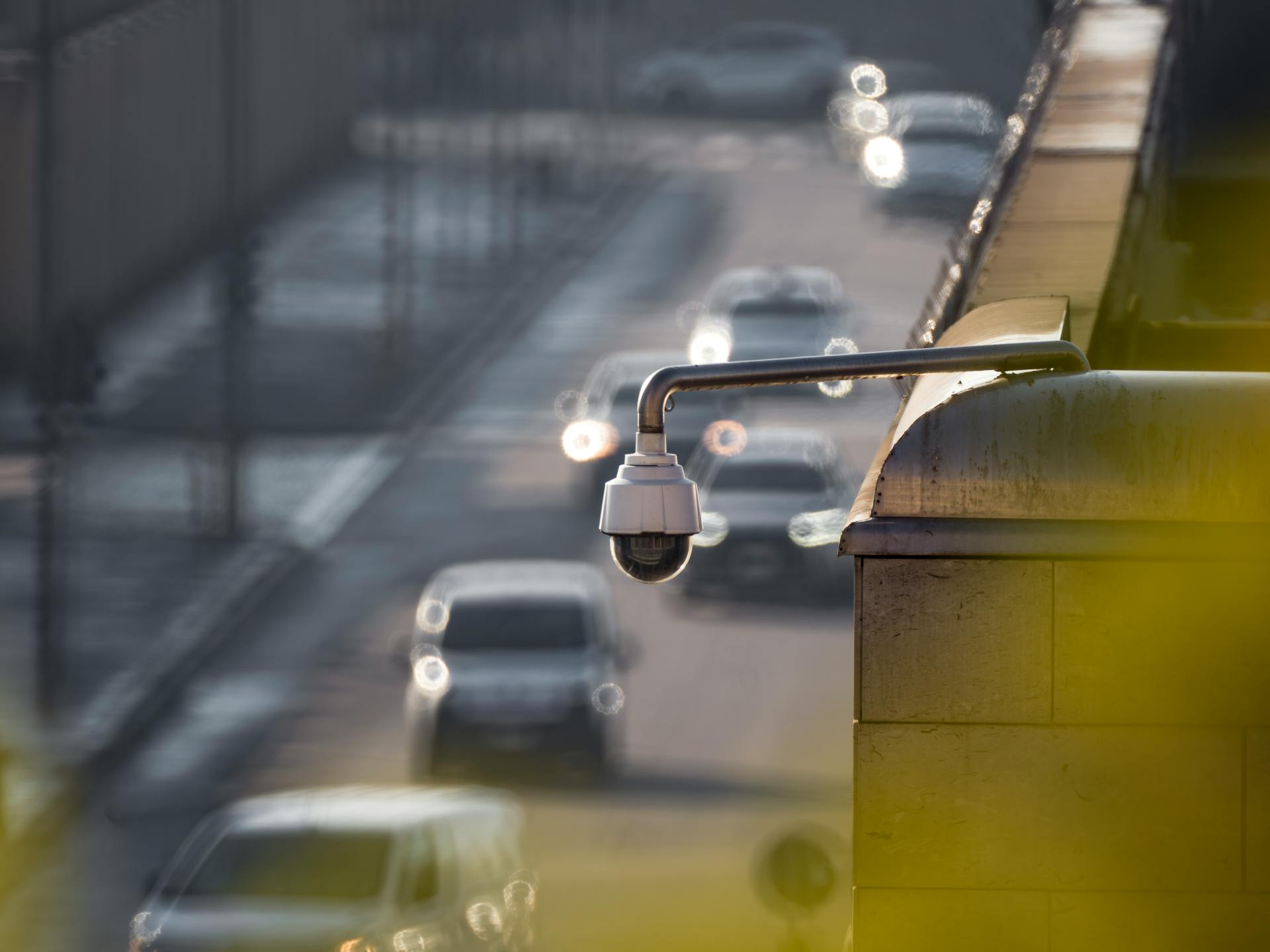 A security camera monitoring activity on a bustling city street with multiple cars in the background.