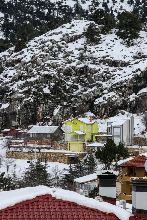 Free Charming snow-covered village nestled in a rugged mountain landscape with vibrant houses. Stock Photo