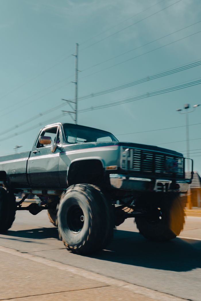 Lifted pickup truck on oversized off-road tires parked on a street