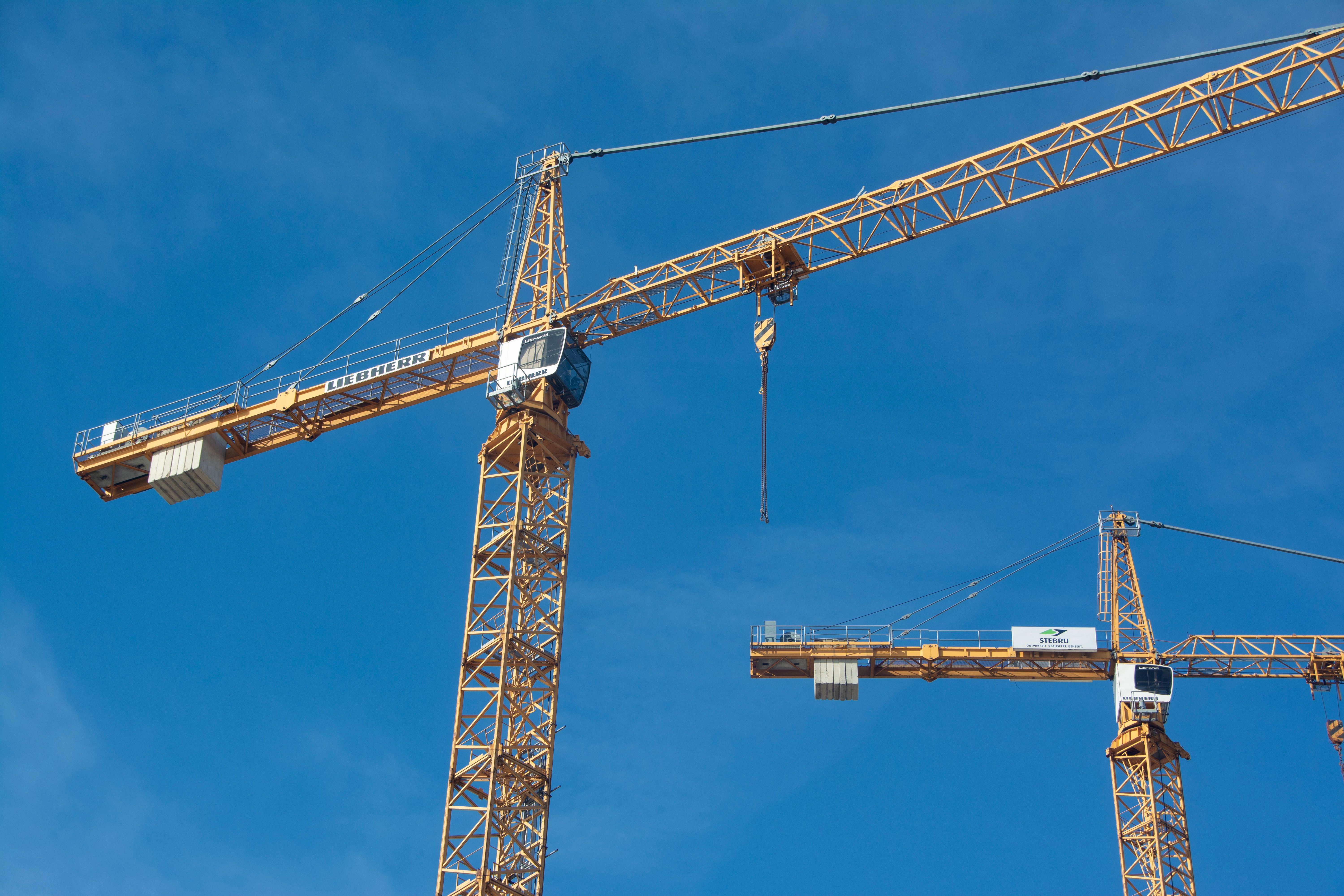 Construction cranes against a bright blue sky