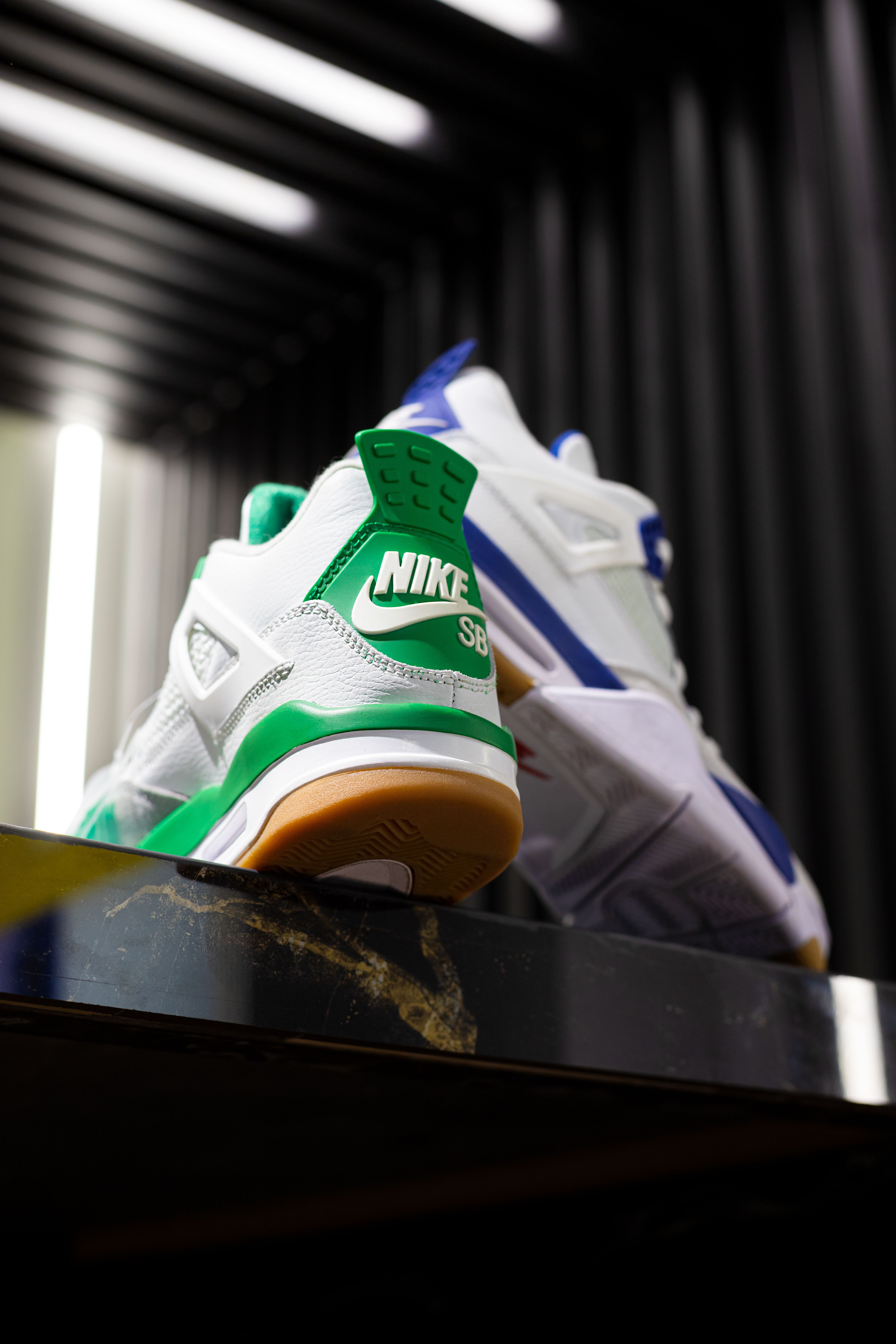 Focus on modern sneakers with vibrant colors displayed on a reflective surface indoors.