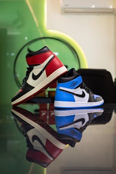 High-top sneakers in red and blue reflecting on glass indoors.