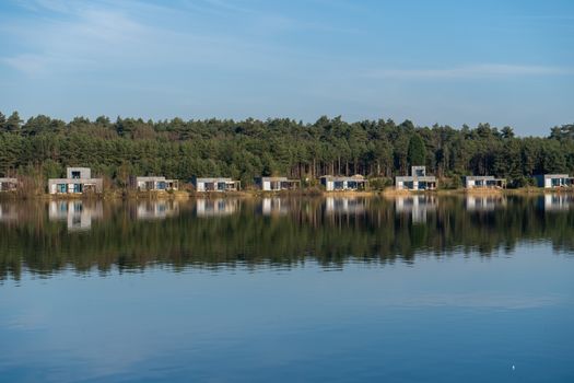Tranquil view of modern cabins reflecting on a lake in Maasmechelen, Belgium.