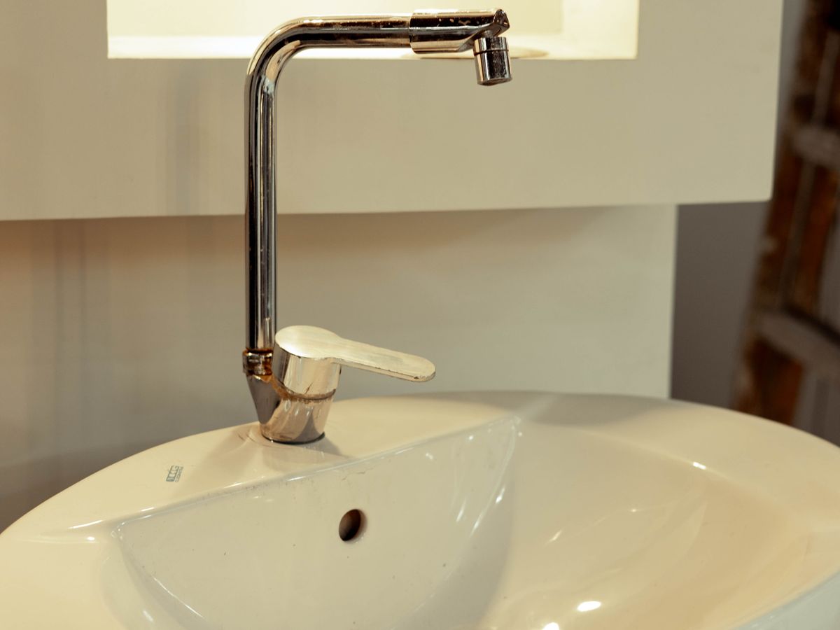 Ceramic sink with a stainless steel faucet under soft lighting.