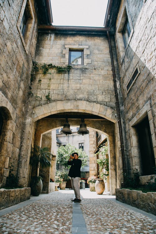 Man Standing on Alleyway Holding Camera