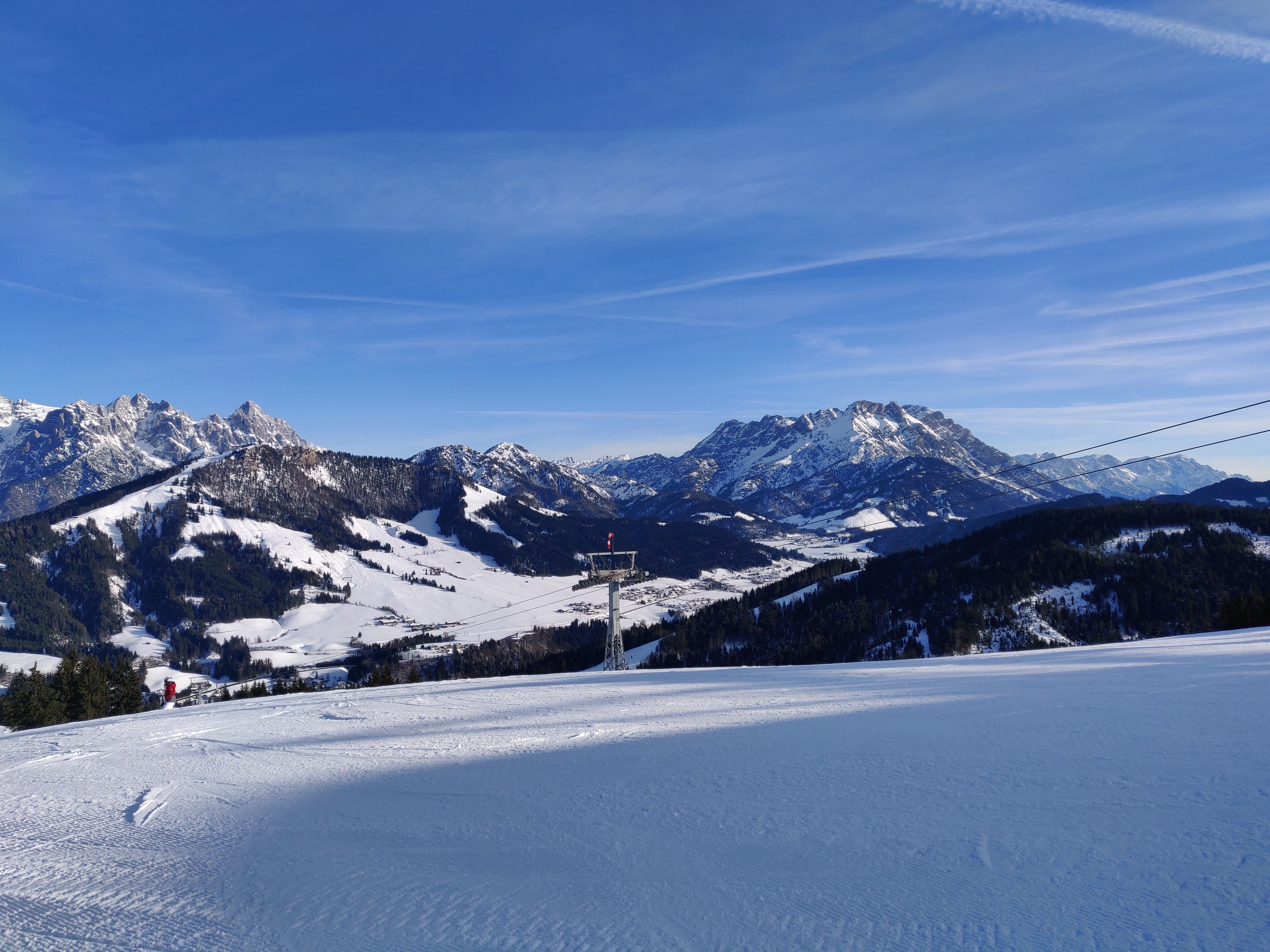 A ski lift climbing above deep snow under a clear Tyrolean sky