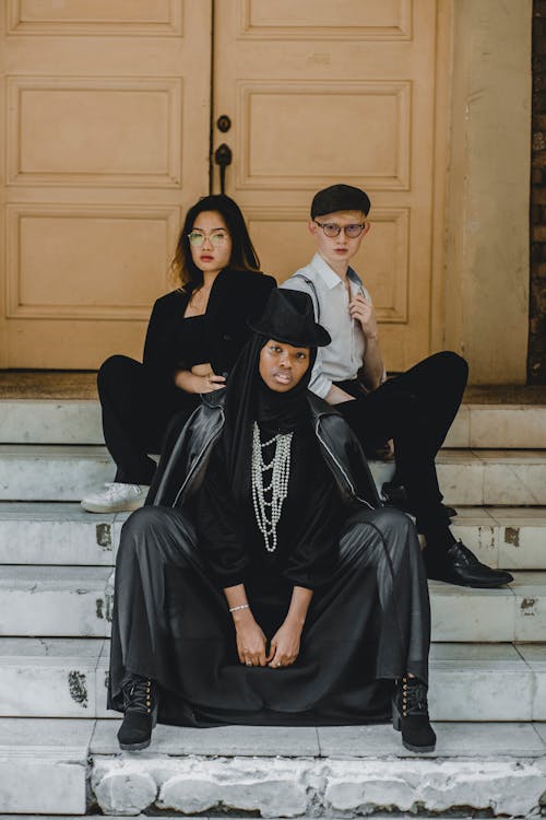 Two Women and Man Sitting on Gray Concrete Stairs