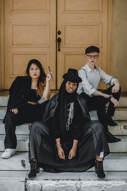 Multiracial man and women in trendy outfits sitting on stairs near door on street