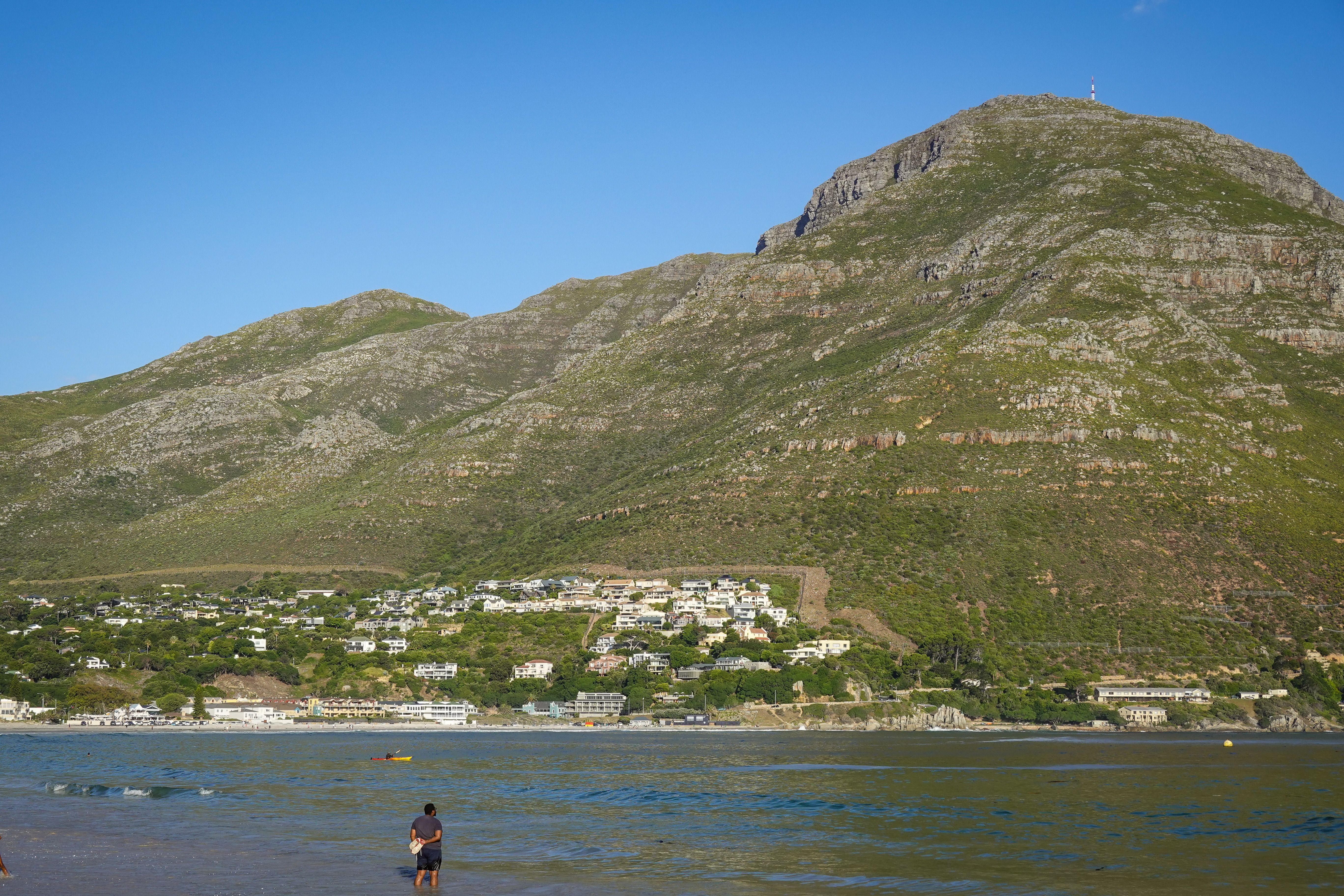 Breathtaking view of the ocean, beach, and mountain landscape on a sunny day.