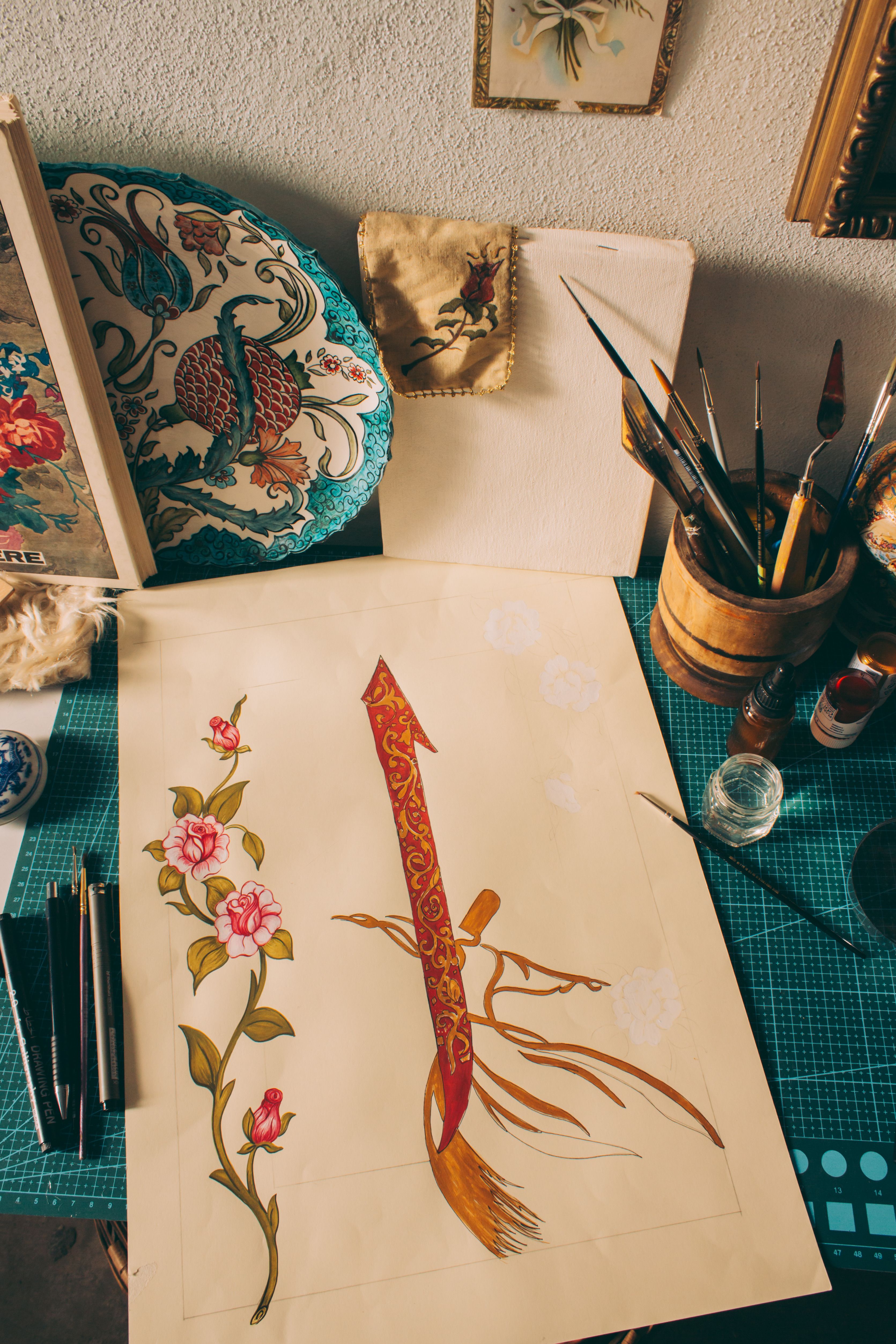 A creative workspace featuring floral art and calligraphy tools, showcasing artistic design.