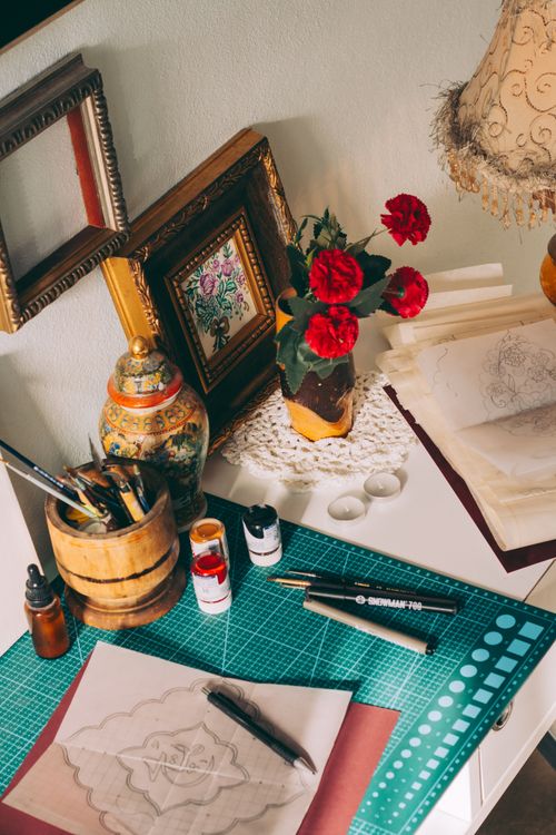 Free Warm-toned art studio with supplies and red flowers, inspiring creativity. Stock Photo