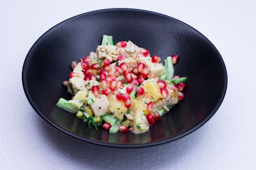 A vibrant pomegranate and cucumber salad served in a black bowl, perfect for healthy eating.