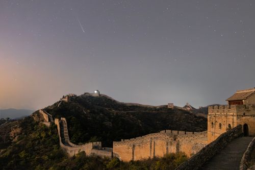 Free The Great Wall of China under a starry night with a visible comet in the sky. Stock Photo