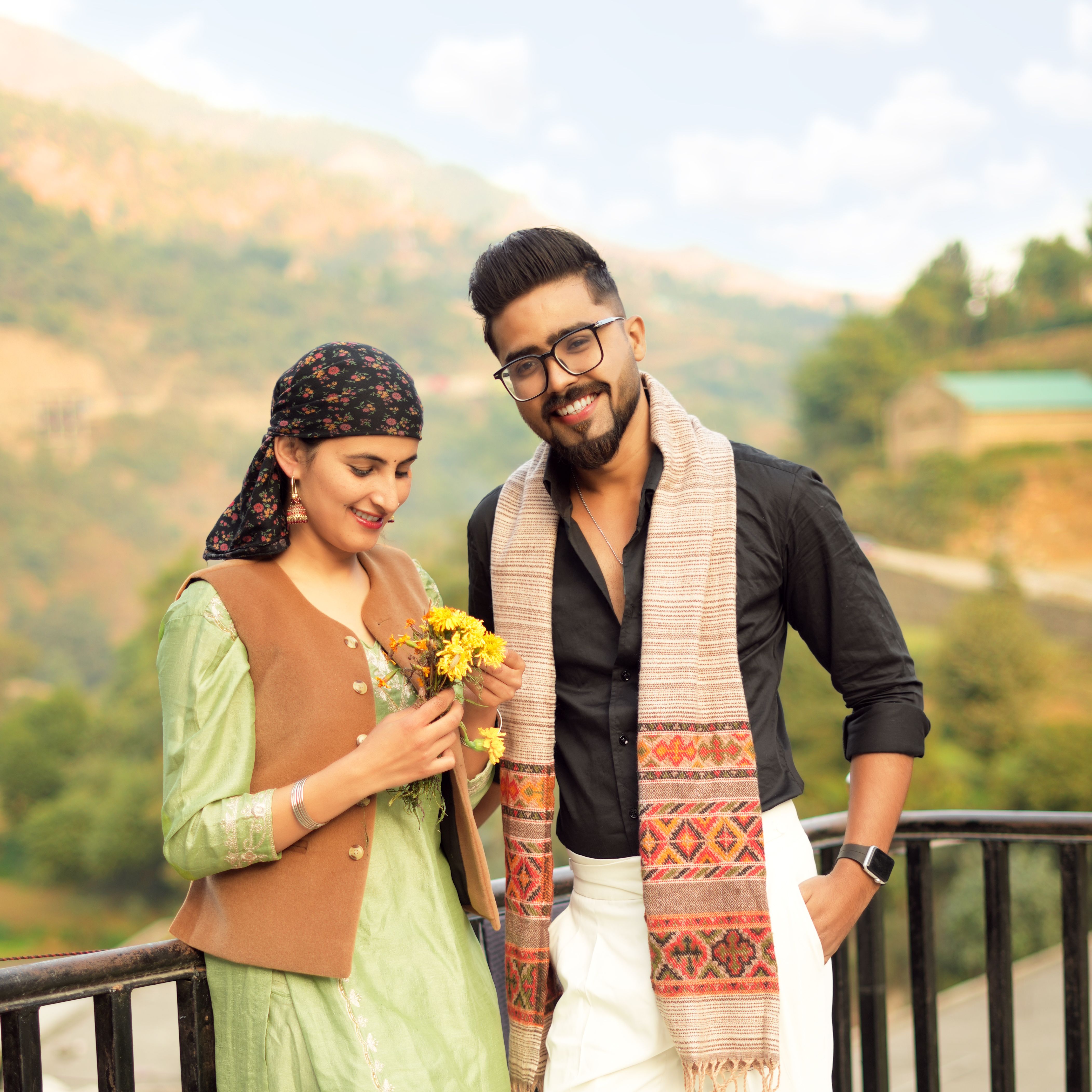 Smiling couple enjoying a scenic outdoor setting with flowers in hand.