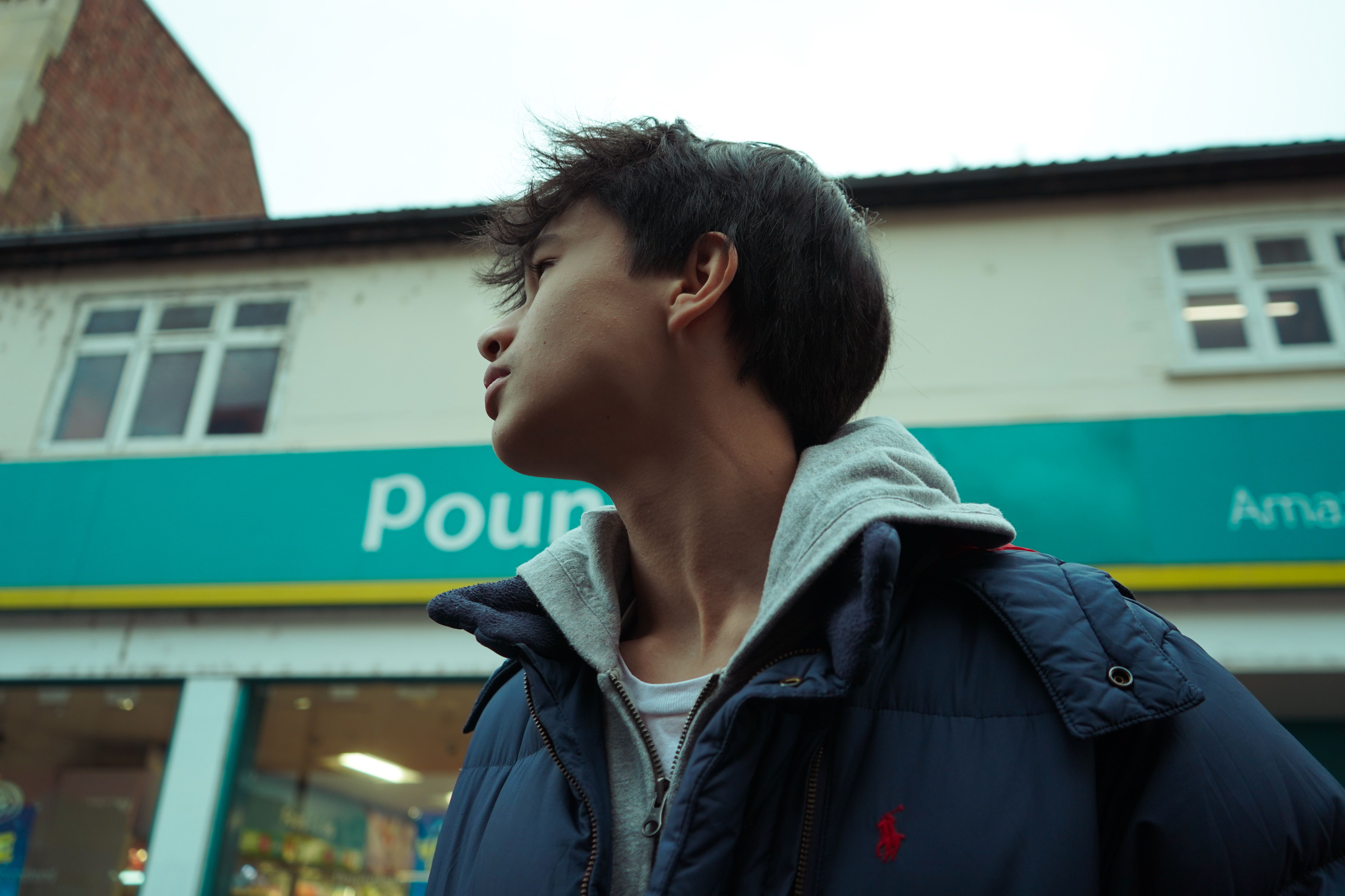 Profile of a young adult in front of urban retail store with signage.
