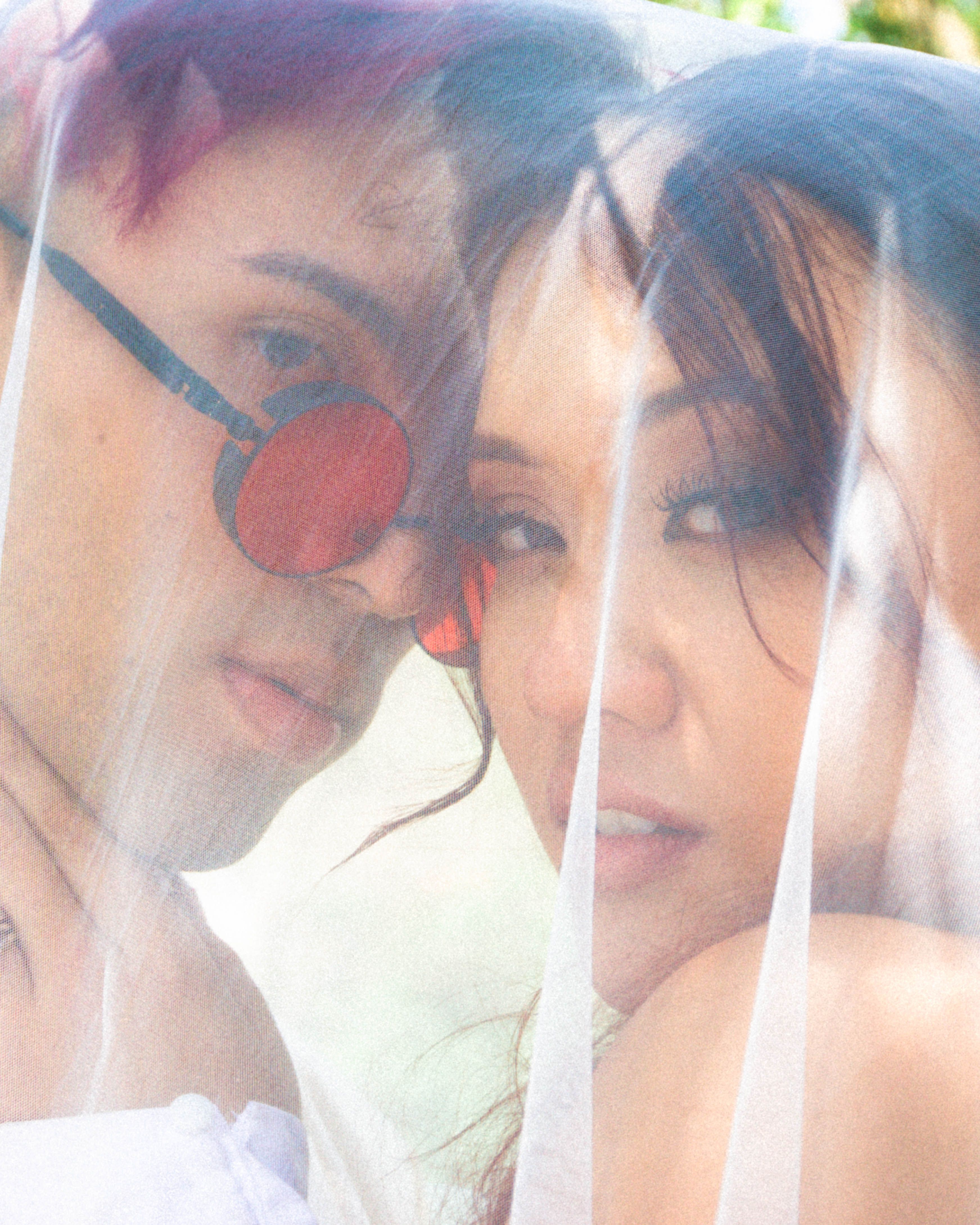 Intimate portrait of a couple under a veil with soft lighting and warm tones.