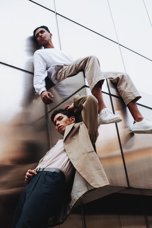 Free Stylish urban photoshoot featuring two young men posing against a mirrored wall. Stock Photo
