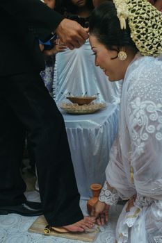 A Sundanese bride participates in a traditional wedding ritual involving a clay jug.