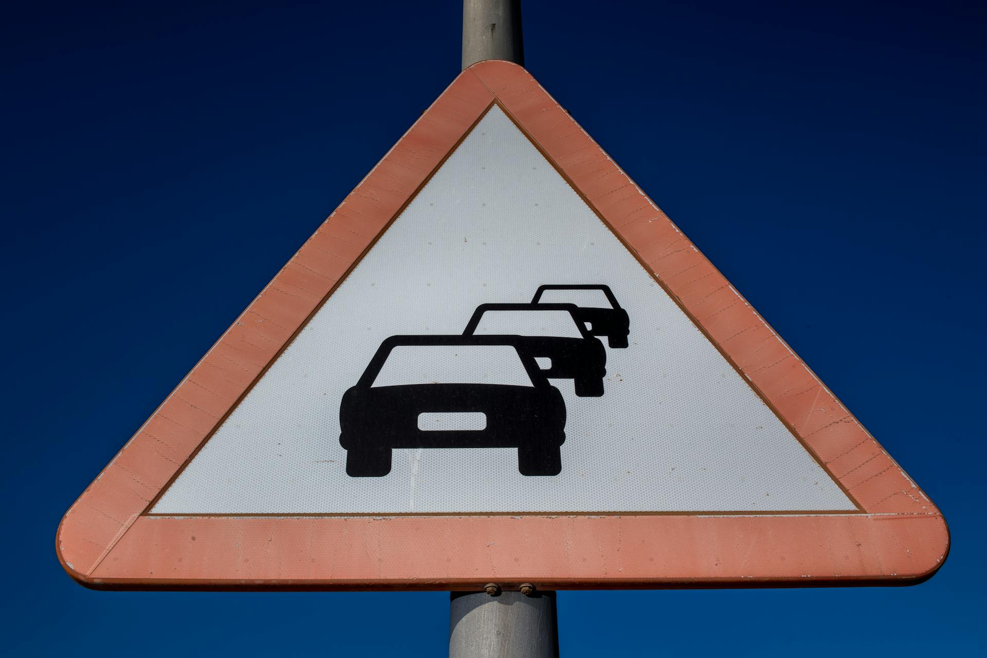 A road traffic warning sign indicating congestion under a clear blue sky.