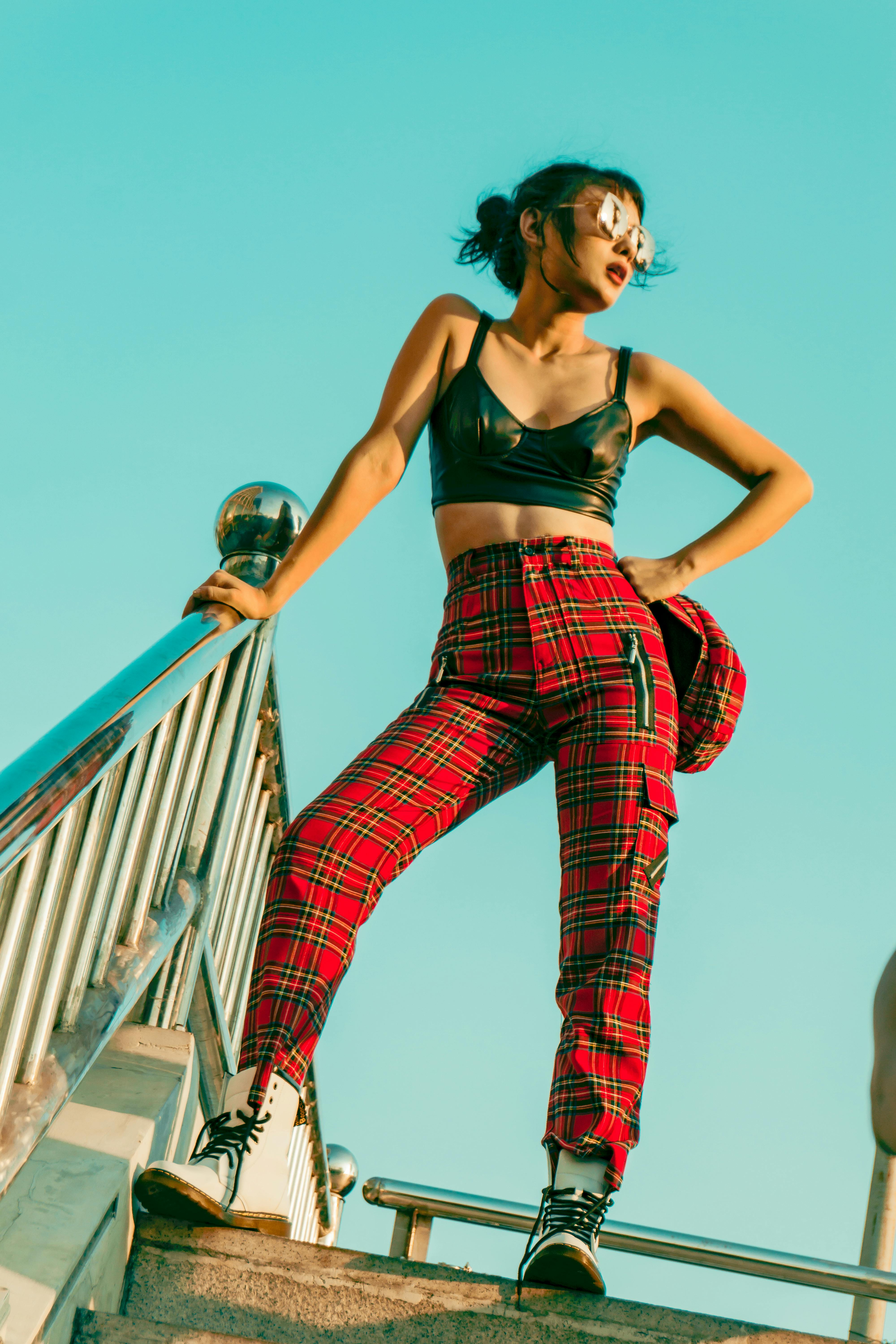 woman in black crop top and red pants standing on gray steps outdoors