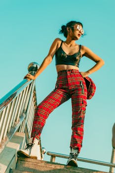 一位自信的年轻女子戴着太阳镜，身着时尚服装，在户外的楼梯上摆姿势