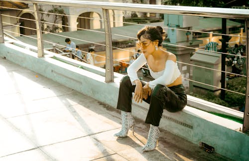 Fashionable young woman sitting outdoors in urban environment with trendy attire.