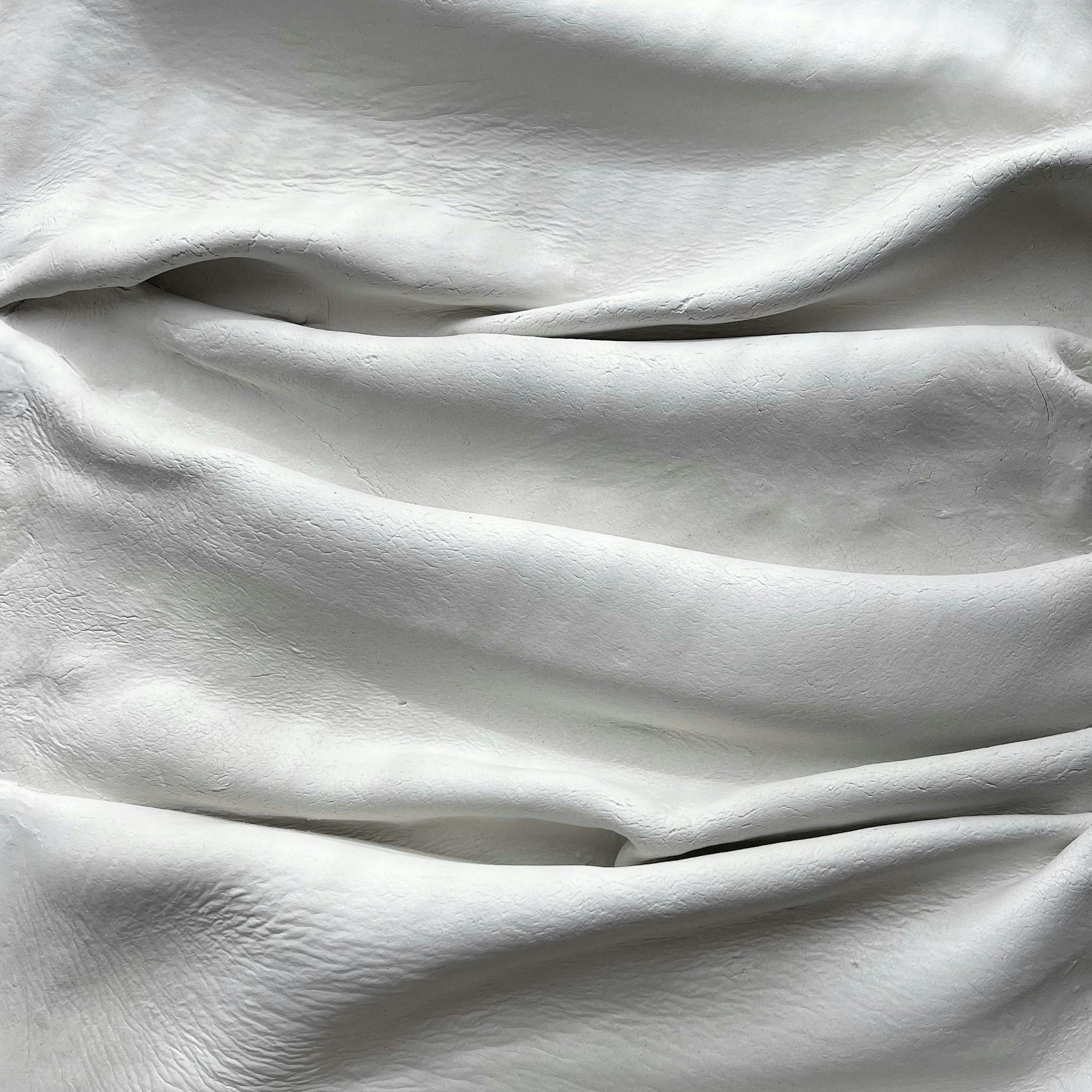 White fabric with soft folds creating an elegant texture and appearance, ideal for backgrounds.