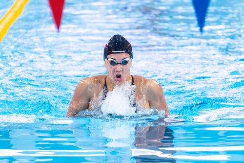 Free Professional swimmer in a race, captured mid-stroke with vibrant pool water. Stock Photo