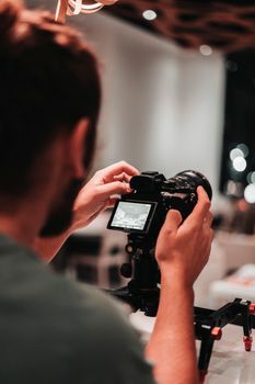 A photographer adjusts camera settings in a creative indoor setting with artistic bokeh lighting.