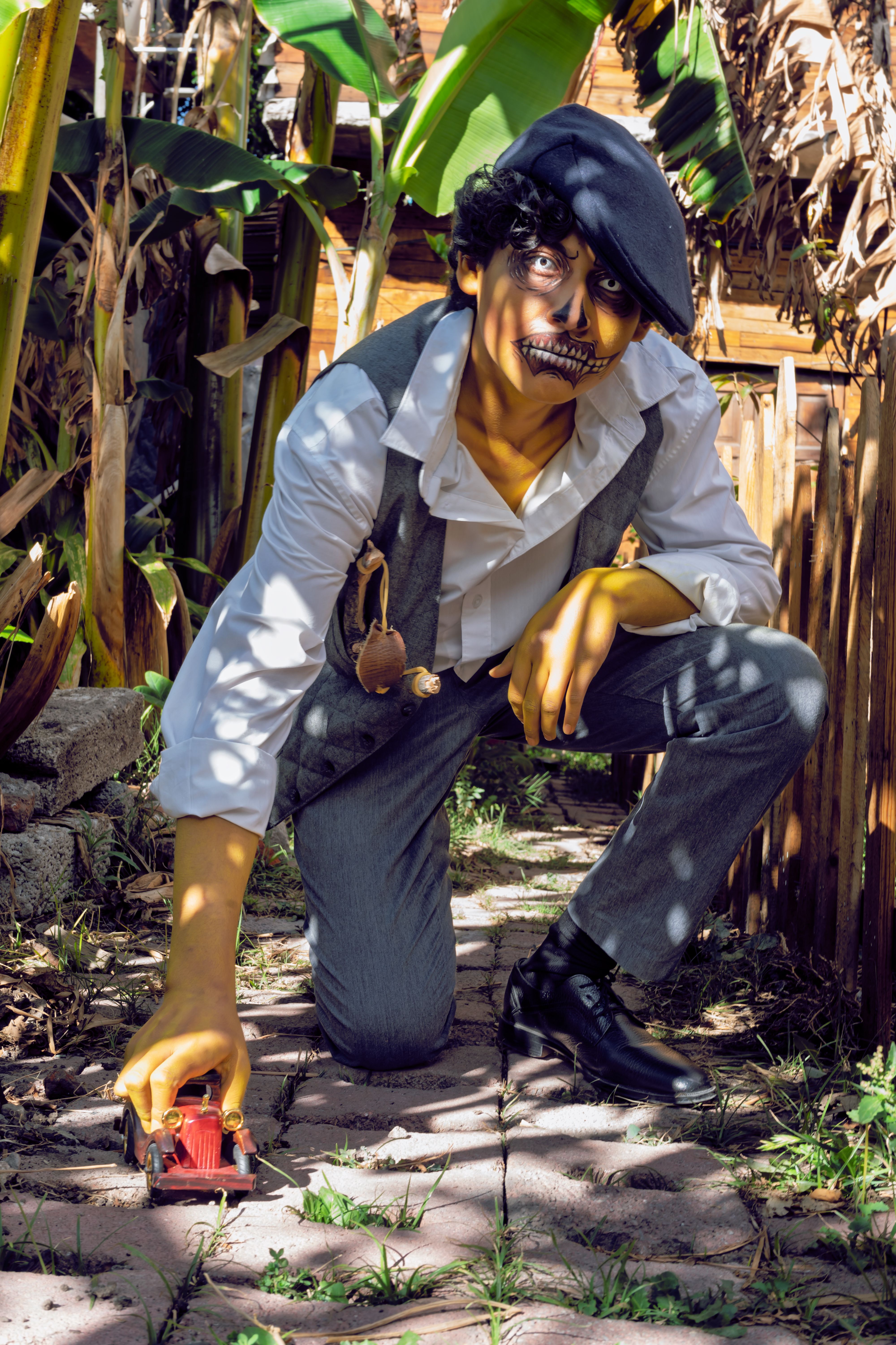 A person wearing a cap and face paint poses outdoors in costume.