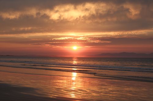 Free Beautiful sunset over a tranquil ocean with a dramatic sky and golden reflections on the water. Stock Photo
