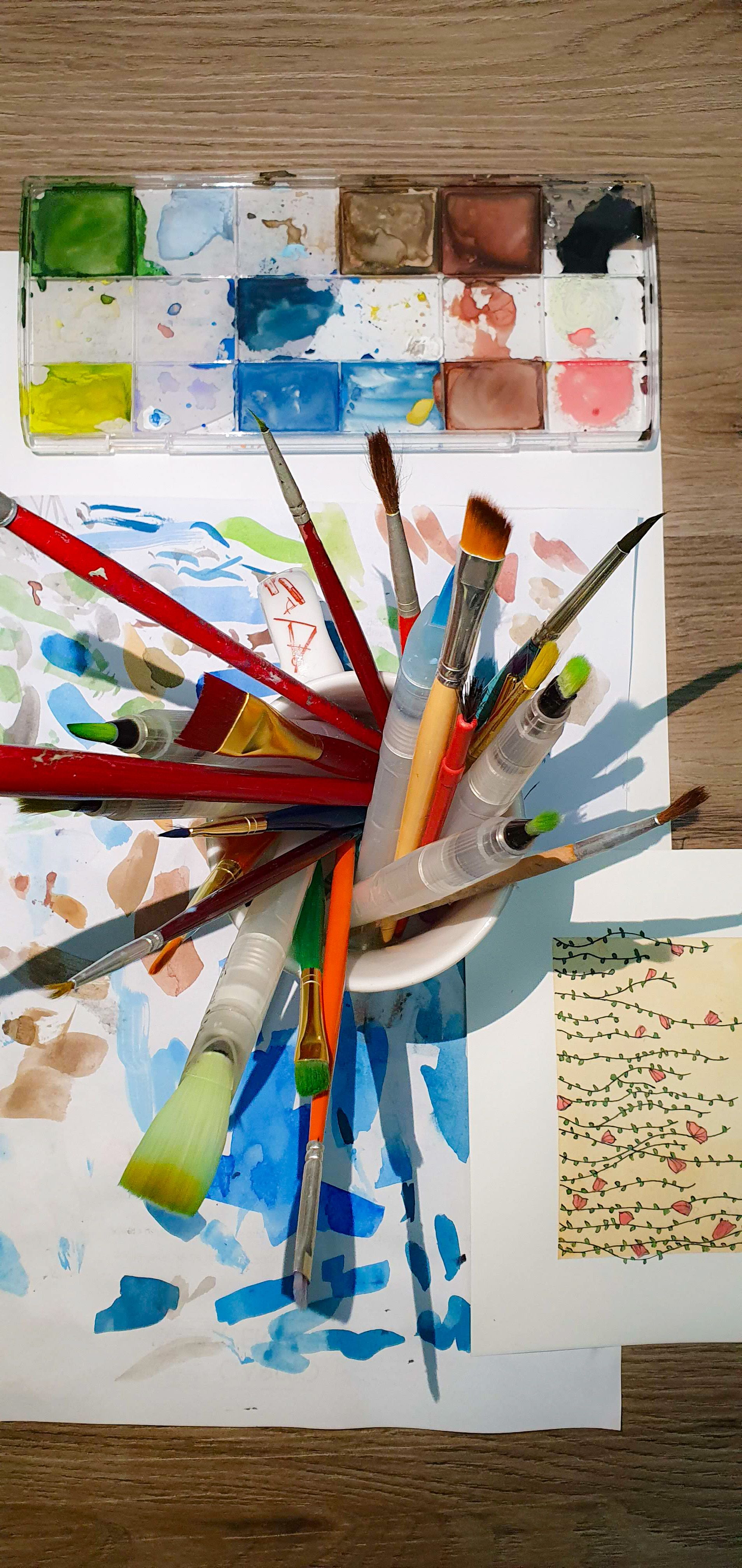 A vibrant artist's workspace with various paint brushes and a watercolor palette.