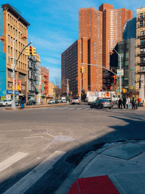 Free Busy city intersection with tall buildings under a clear blue sky. Stock Photo