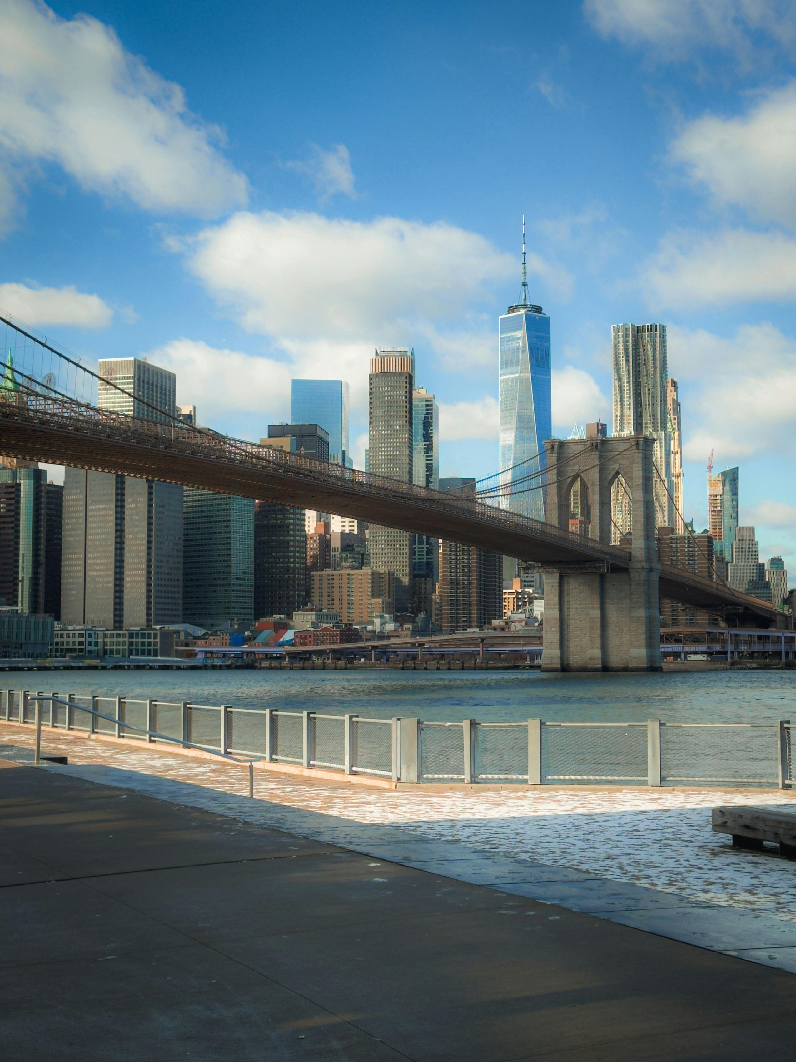 Scenic view of Brooklyn Bridge with Manhattan skyscrapers under a blue sky.