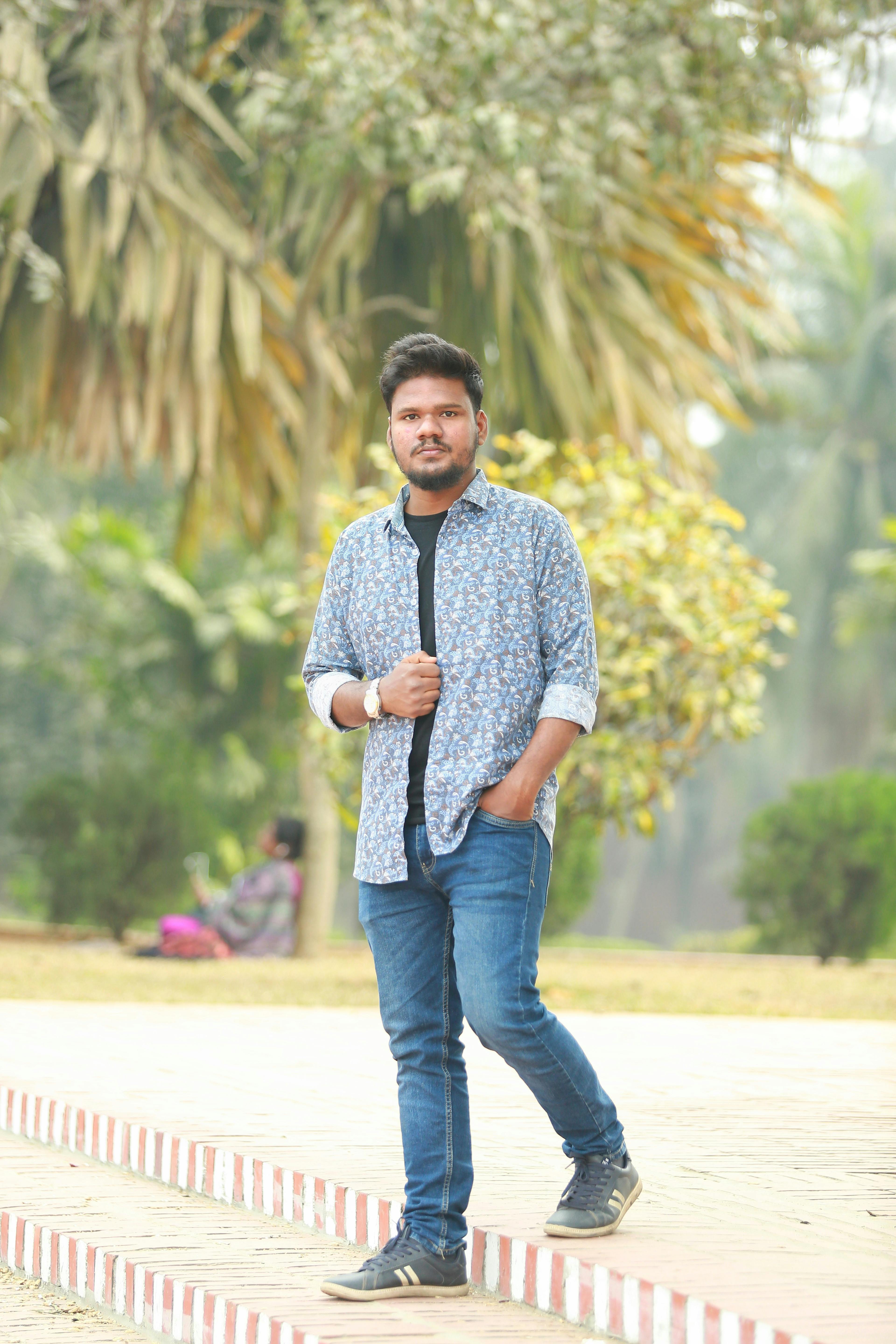 A young man in casual clothing walking confidently in a sunny park.