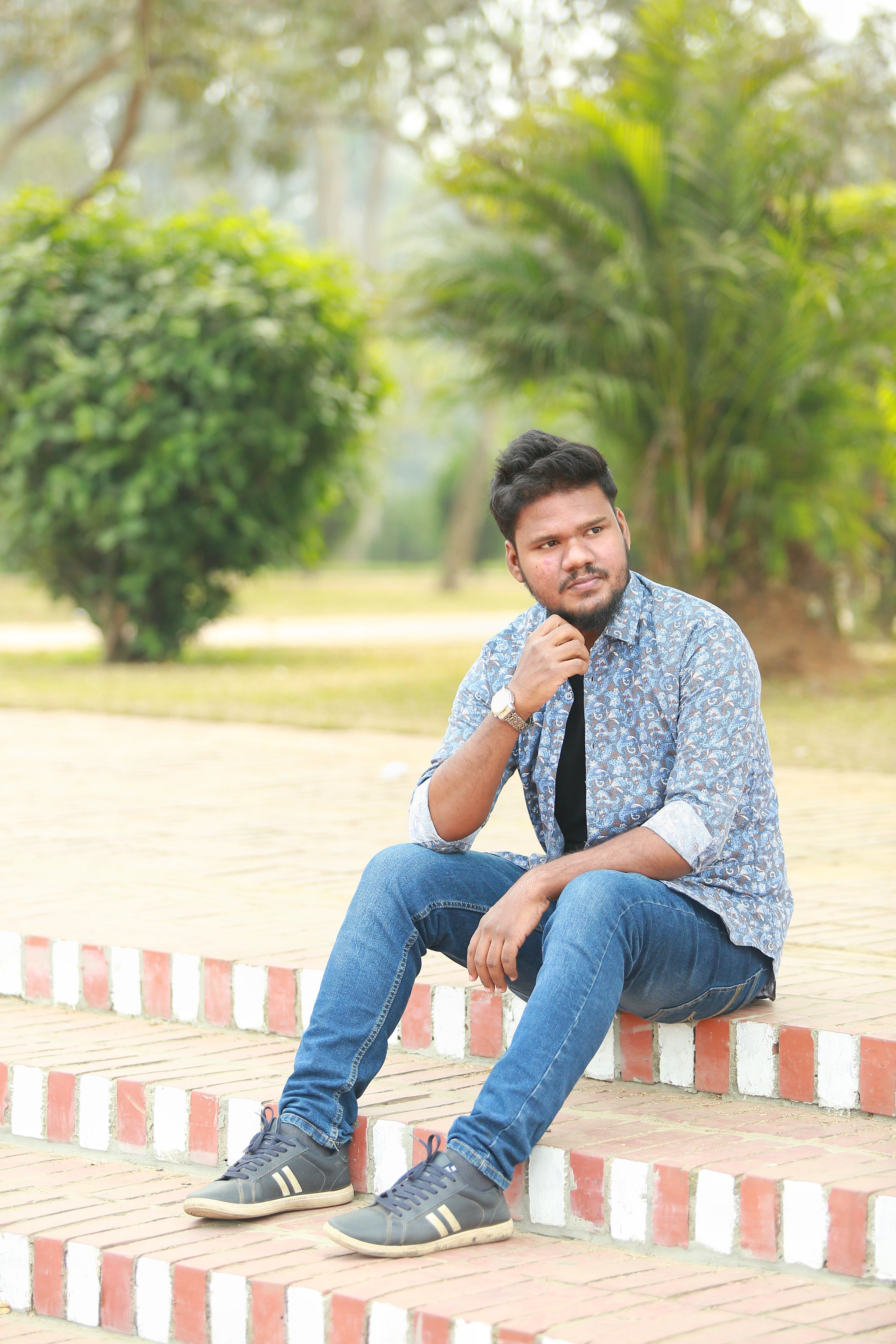 Young man wearing casual fashion seated on outdoor steps in Dhaka, Bangladesh.